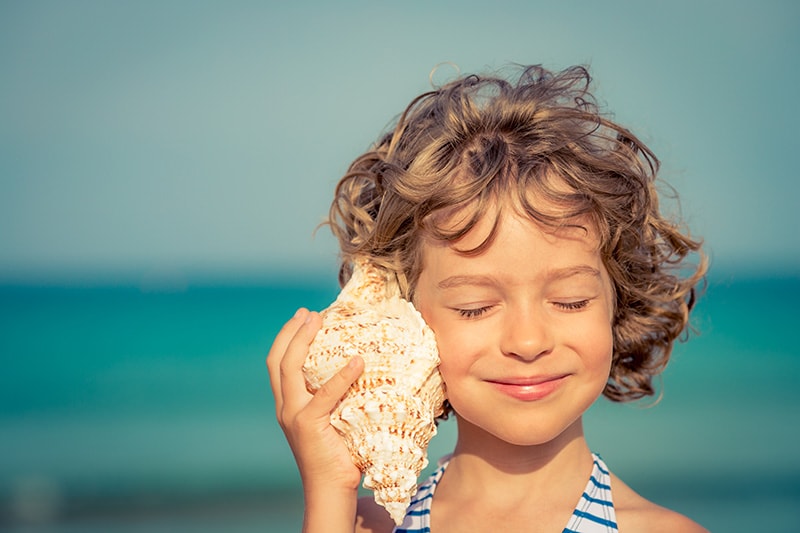 Child relaxing on the beach against sea and sky background. Summer vacation and travel concept