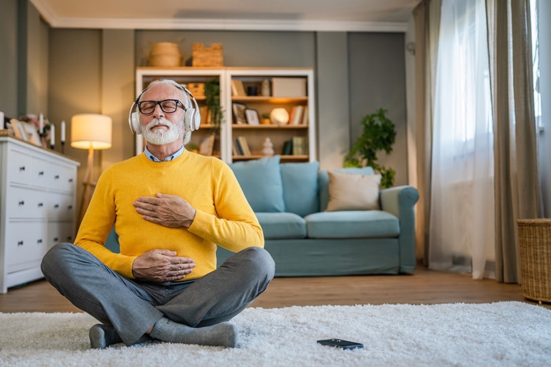 one man mature senior caucasian male using headphones for online guided meditation practicing mindfulness yoga manifestation with eyes closed at home real people self care concept copy space