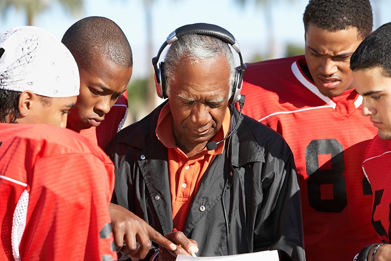 Football players and coach discussing strategy together