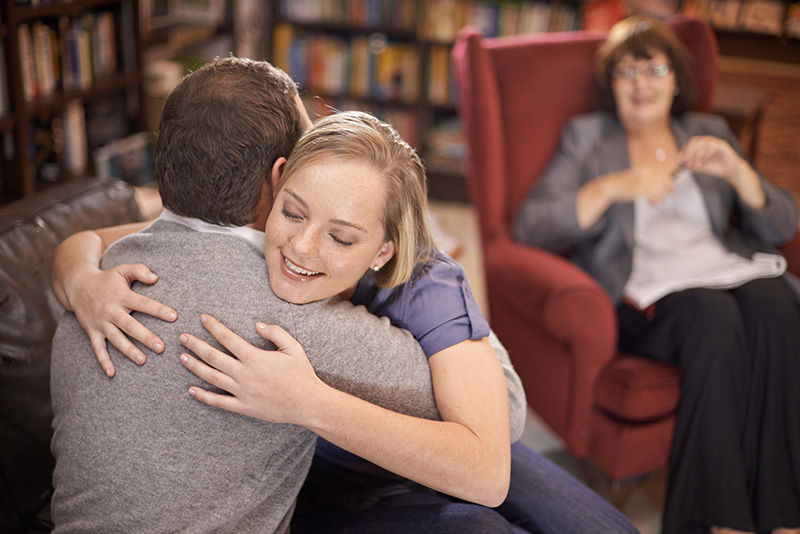 Couple embracing with coach in the background