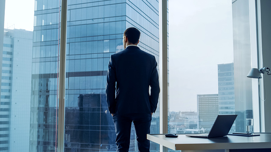 CEO contemplating, looking out over high rise cityscape